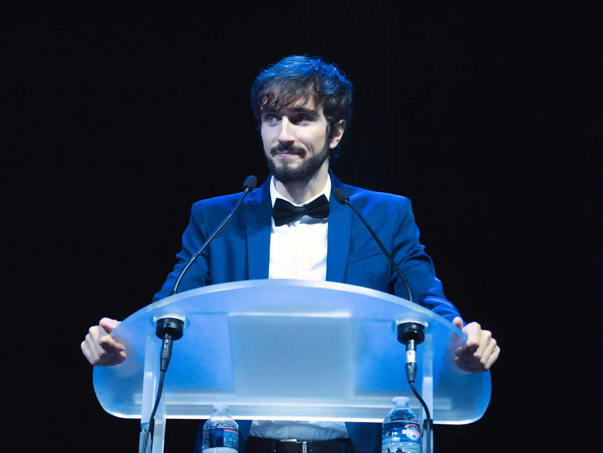 Host delivering a speech from a podium during a corporate gala dinner awards segment