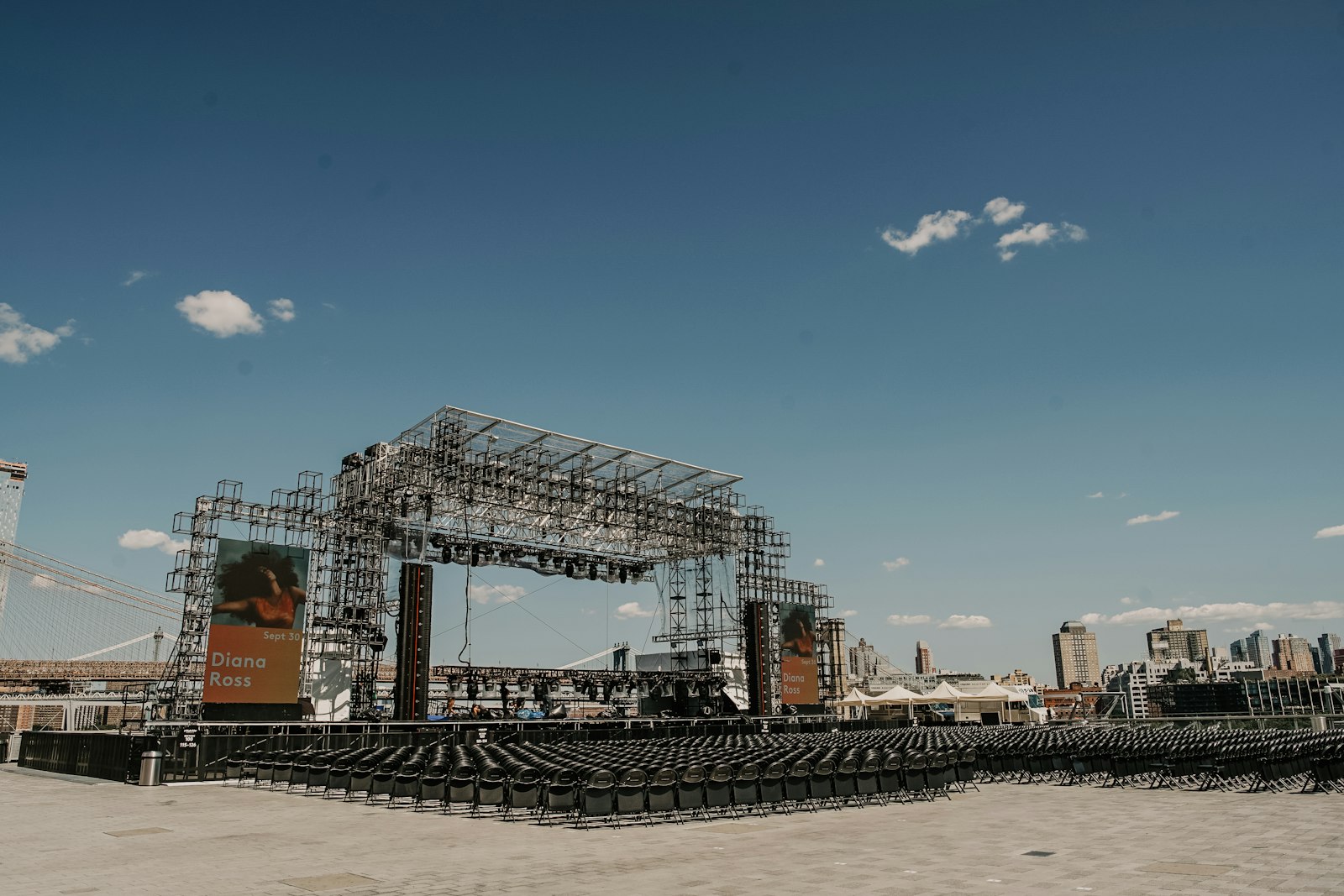 Outdoor event stage with truss structure and audience seating being prepared before a show