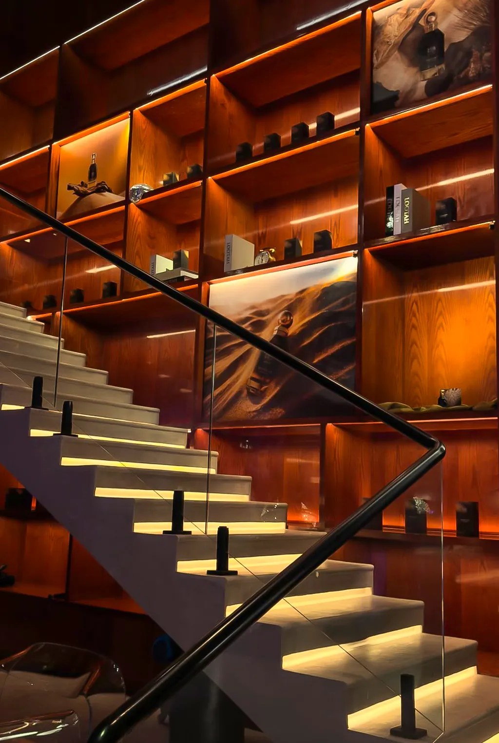 Lootah display shelves and illuminated staircase at Someone’s House, with Desert Oud artwork