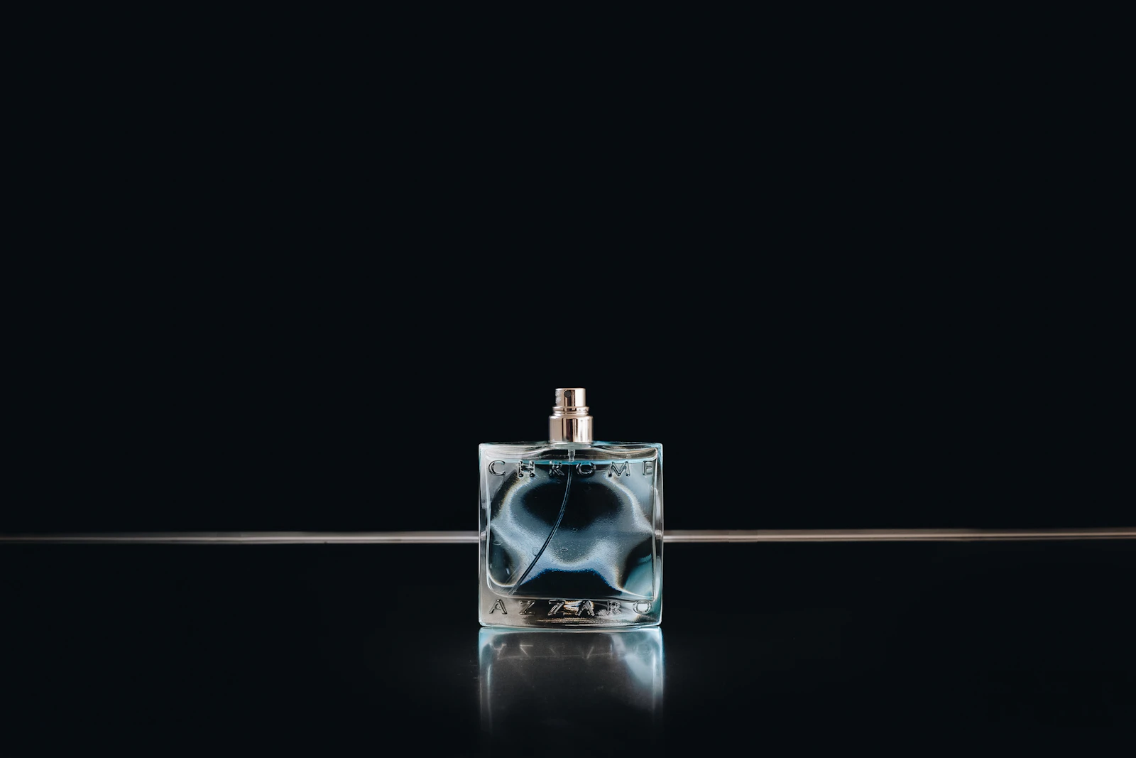Glass fragrance bottle photographed against a dark backdrop for a product advertisement Glass fragrance bottle photographed against a dark backdrop for a product advertisement