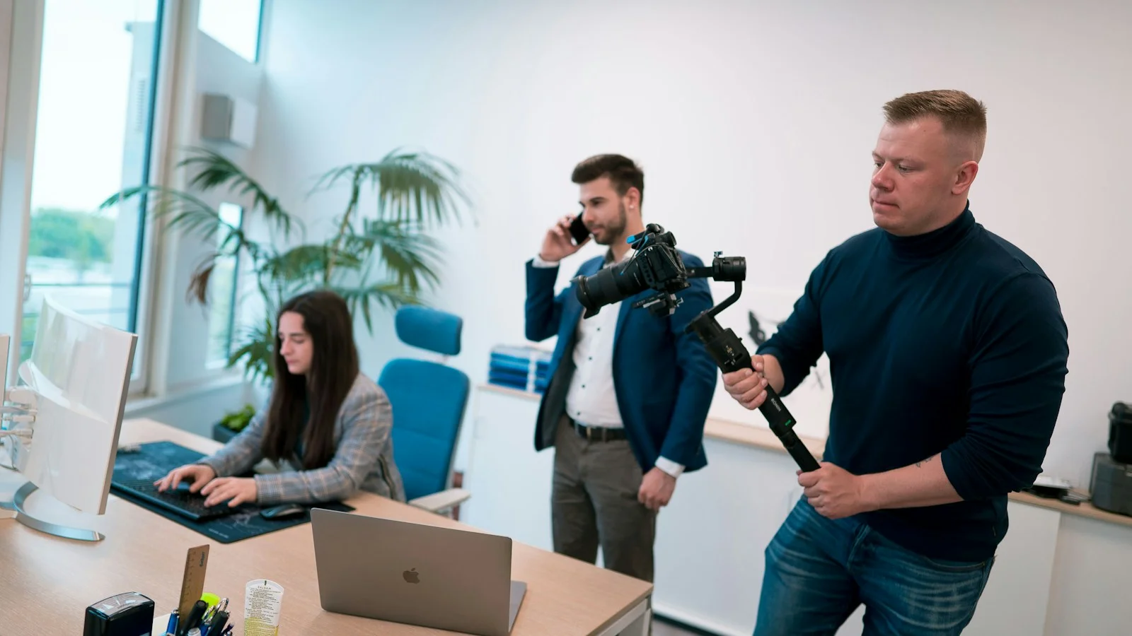 Videographer filming an employee at work in an office for testimonial footage